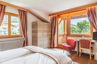 a bedroom with a bed and a desk and a window at Hotel Erna in Colle Isarco