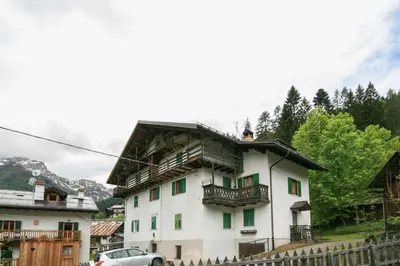 a large white house with a car parked in front of it at Casa Silva in Falcade