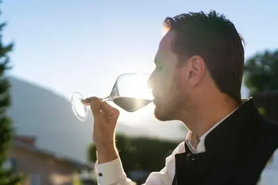 a man drinking a glass of white wine at Hotel Alpenhof in Tirolo