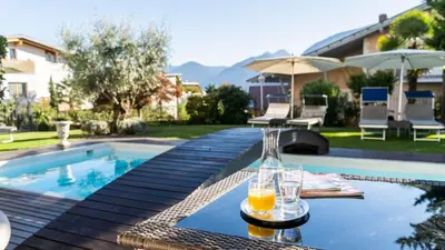 a glass of orange juice sitting on a table next to a swimming pool at Hotel Alpenhof in Tirolo
