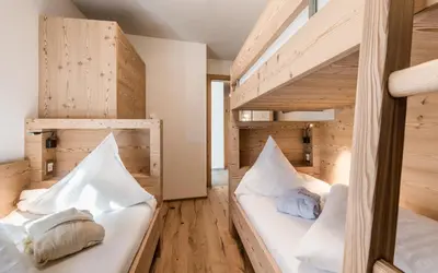 two bunk beds in a room with wooden walls at Hotel Gasserhof in Bressanone