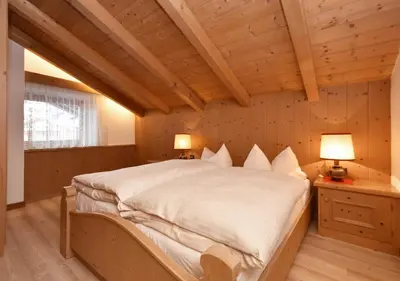a bedroom with a large bed in a wooden ceiling at Post Hotel Moena in Moena