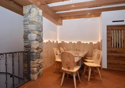 a restaurant with tables and chairs and a stone wall at Post Hotel Moena in Moena