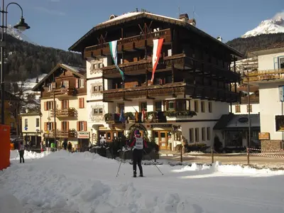 a person on skis in the snow in front of a building at Post Hotel Moena in Moena