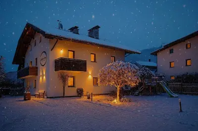 a building with a tree in the snow at night at Apartment Obermair in Brunico