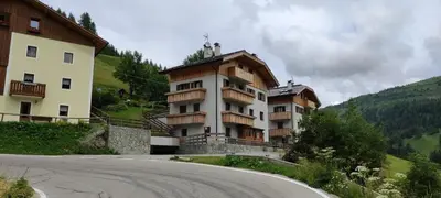 a building on a hill next to a road at Appartamento Gliera in Arabba