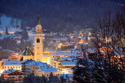 a city with a clock tower in the snow at night at CanguroProperties - Ca' Mora in Cortina dʼAmpezzo