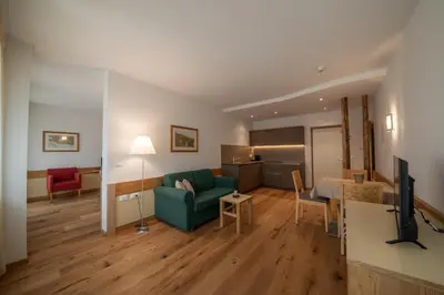 a living room with a green couch and a kitchen at Pöder - daheim in den Bergen in Ultimo