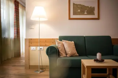 a living room with a green couch and a lamp at Pöder - daheim in den Bergen in Ultimo
