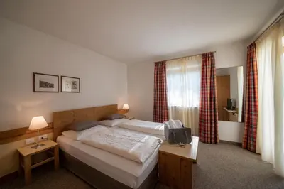 a bedroom with two beds and a television in it at Pöder - daheim in den Bergen in Ultimo