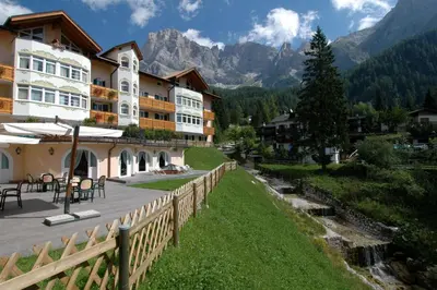 a hotel with a fence next to a river at Residence Pez Gajard in San Martino di Castrozza