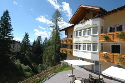 a building with a table and chairs in front of it at Residence Pez Gajard in San Martino di Castrozza