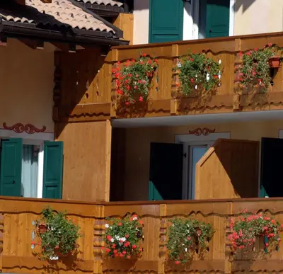 a building with green shutters and flowers on a balcony at Residence Pez Gajard in San Martino di Castrozza