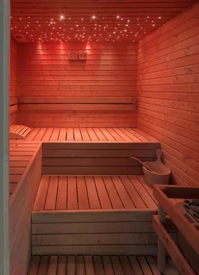 a wooden sauna with a bench and lights in it at Parkhotel Fedora in Campitello di Fassa