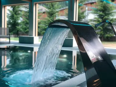 a water fountain in a pool in front of a building at Parkhotel Fedora in Campitello di Fassa