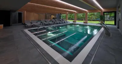 a large swimming pool with chairs in a building at Parkhotel Fedora in Campitello di Fassa