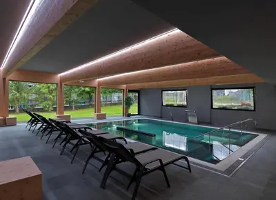 a swimming pool with chairs in a room with windows at Parkhotel Fedora in Campitello di Fassa
