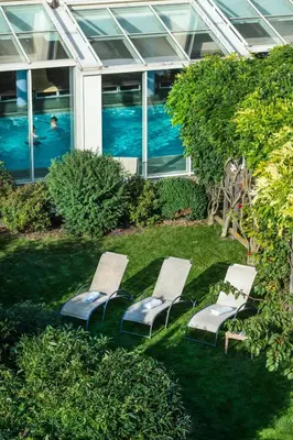 three lounge chairs sitting in the grass in front of a building at Hotel St. Anton in Fiè