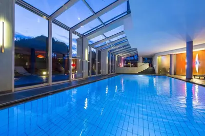 a swimming pool with a large window and a building at Hotel St. Anton in Fiè