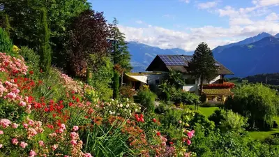 a garden with flowers in front of a house at Tirolerhof Tisens in Tesimo