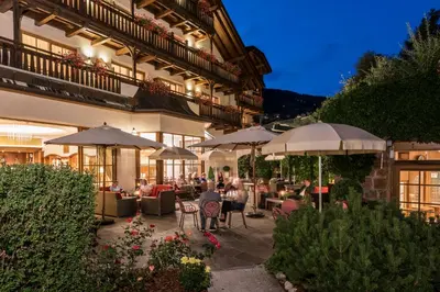 a restaurant with tables and chairs and umbrellas at Hotel Angelo Engel in Ortisei