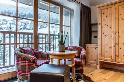 a living room with a table and chairs and a large window at Hotel Angelo Engel in Ortisei