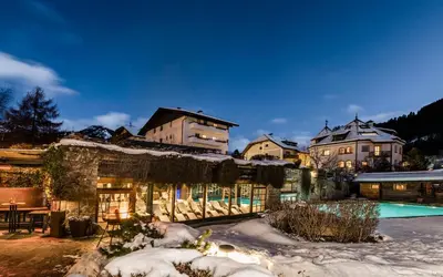 a large house with a swimming pool in the snow at Hotel Angelo Engel in Ortisei