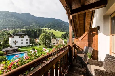 a living room with a table and chairs and a large window at Hotel Angelo Engel in Ortisei