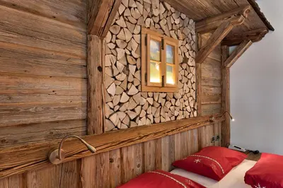a bedroom with a log wall and a bed with red pillows at Alpenhotel Panorama in Campitello di Fassa