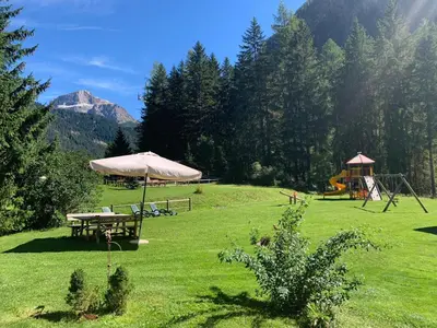 a field with a picnic table and a tent at Alpenhotel Panorama in Campitello di Fassa