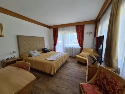 a bedroom with a bed and a flat screen tv at Alpenhotel Panorama in Campitello di Fassa