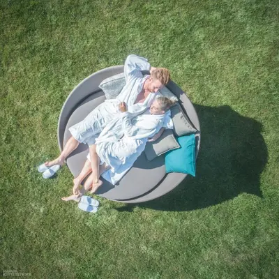 a woman and child laying on a bed in the grass at Molaris Lodge in Mühlbach