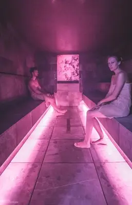 two people sitting on beds in a dark room at Molaris Lodge in Mühlbach