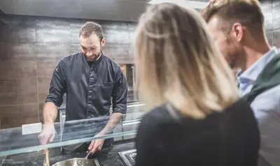 a man and a woman preparing food in a kitchen at Molaris Lodge in Mühlbach