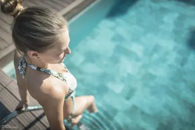 a young girl sitting in a chair by a pool at Molaris Lodge in Mühlbach