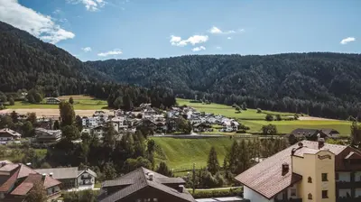 a village in the mountains with houses and trees at Smy Koflerhof Wellness & Spa Dolomiti in Rasun di Sopra