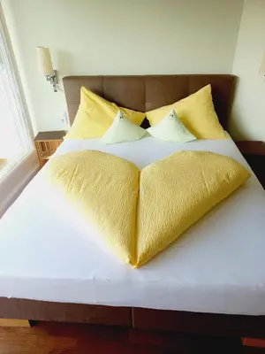 a large bed with yellow pillows on it at Villa Raifer in Appiano sulla Strada del Vino