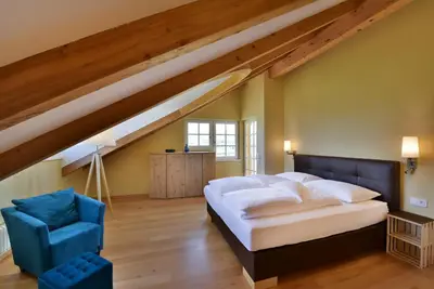 a bedroom with a bed and a blue chair at Villa Raifer in Appiano sulla Strada del Vino