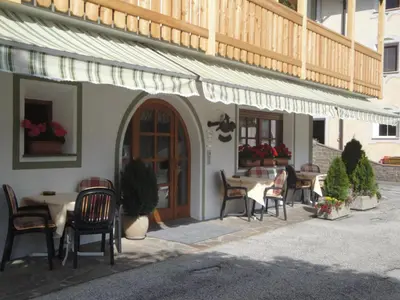a patio with tables and chairs in front of a building at Garni Halali in Ortisei