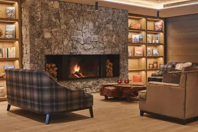 a living room with a fireplace and a couch and a chair at Hotel Olangerhof in Valdaora