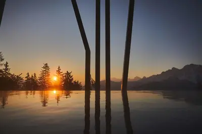 a sunset over a lake with palm trees in the foreground at Hotel Olangerhof in Valdaora