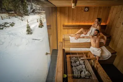 a man and a woman sitting in a sauna at Hotel Olangerhof in Valdaora