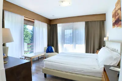 a hotel room with a bed and a desk and windows at Hotel Trento in Pozza di Fassa