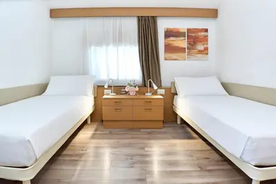 two beds in a hospital room with a desk at Hotel Trento in Pozza di Fassa