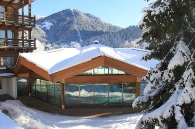 a building with a snow covered roof in the snow at Hotel Trento in Pozza di Fassa