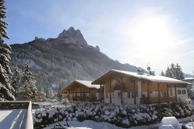 a ski lodge with a mountain in the background at Hotel Trento in Pozza di Fassa