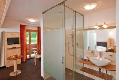 a bathroom with a glass shower and a sink at Hotel Schennerhof in Schenna