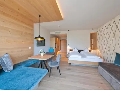 a bedroom with a bed and a table and chairs at Hotel Schennerhof in Schenna