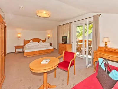 a hotel room with a bed and a table and a chair at Hotel Schennerhof in Schenna