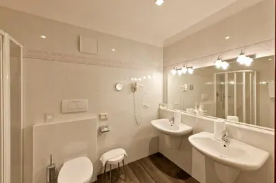 a white bathroom with two sinks and a mirror at Hotel Schennerhof in Schenna